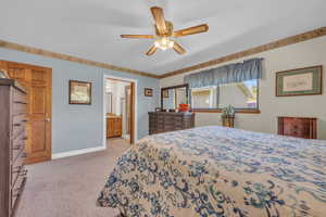 Master Bedroom with ensuite bathroom, light carpet, and ceiling fan