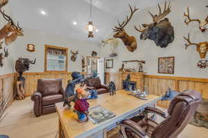 Trophy room built next to garage. Multi purpose bonus room. Carpeted space featuring wood walls and vaulted ceiling