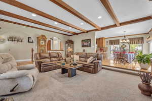 Living room, ornamental molding, light colored carpet, and beamed ceiling