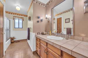 Main upstairs bathroom featuring tile patterned flooring, bath / shower combo with glass door, and vanity