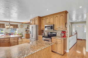 Kitchen featuring hanging light fixtures, tasteful backsplash, light wood-type flooring, and stainless steel appliances