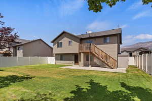 Rear view of house featuring a patio, a lawn, and a mountain view