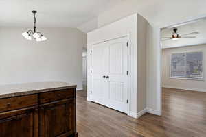 Dining room with ceiling fan with notable chandelier, vaulted ceiling, and light wood-type flooring