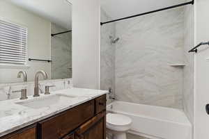 Full bathroom featuring vanity, tiled shower / bath combo, and toilet