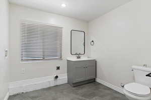 Large laundry room with 1/2 bath with  tile patterned floors, toilet, and vanity