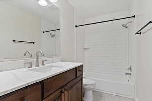 Full bathroom featuring tile patterned floors, vanity, tiled shower / bath combo, and toilet