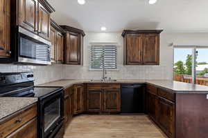 Kitchen featuring black appliances, tasteful backsplash, light wood-type flooring, sink, and kitchen peninsula