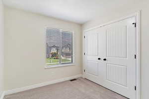 Unfurnished bedroom featuring light carpet and a closet