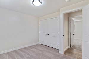 Unfurnished bedroom with a closet and light colored carpet