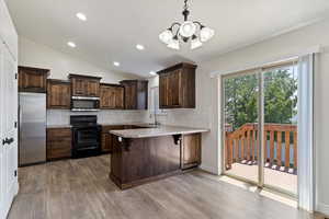 Kitchen featuring lofted ceiling, light hardwood / wood-style floors, stainless steel appliances, and backsplash