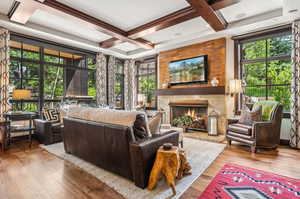 Living room featuring coffered ceiling, light wood-type flooring, and plenty of natural light