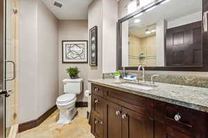 Bathroom featuring tile patterned floors, vanity, walk in shower, and toilet