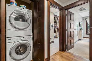 Laundry room featuring light carpet and stacked washing maching and dryer