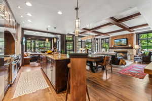 Kitchen with hanging light fixtures, wood-type flooring, a fireplace, and a center island with sink