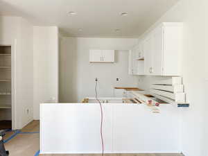 Kitchen with white cabinets, a textured ceiling, and light hardwood / wood-style floors