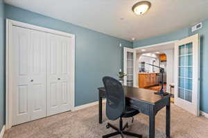 Home office with light colored carpet and french doors