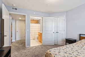 Bedroom with a closet, connected bathroom, and light colored carpet