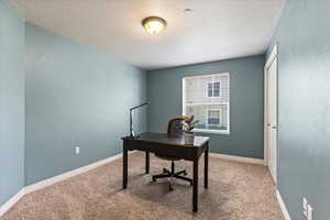 Carpeted office featuring a textured ceiling