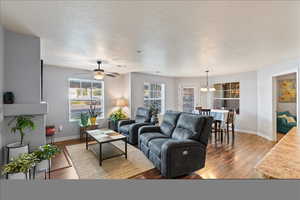 Living room featuring ceiling fan with notable chandelier and hardwood / wood-style flooring