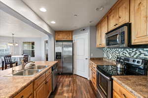 Kitchen with tasteful backsplash, stainless steel appliances, sink, dark hardwood / wood-style flooring, and a notable chandelier