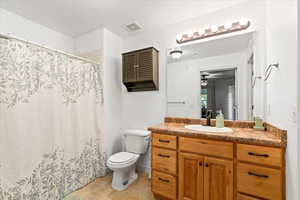 Master bathroom featuring tile patterned floors, vanity, ceiling fan, and toilet