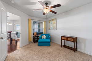 Sitting room featuring ceiling fan with notable chandelier and wood-type flooring