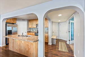 Kitchen featuring stainless steel appliances, decorative backsplash, sink, a center island with sink, and dark hardwood / wood-style floors