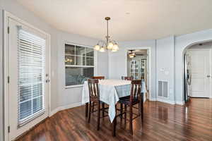 Dining area featuring dark hardwood / wood-style flooring and ceiling fan with notable chandelier