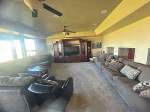 Home theater featuring carpet floors, ceiling fan, and a raised ceiling