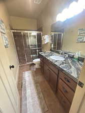 Bathroom with tile patterned flooring, a shower with door, toilet, and vanity