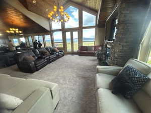 Living room featuring wooden ceiling, a wealth of natural light, an inviting chandelier, and carpet