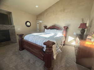 Carpeted bedroom featuring a fireplace and vaulted ceiling