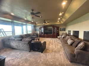 Carpeted cinema featuring ceiling fan and a raised ceiling