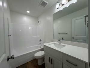 Full bathroom featuring LVP flooring, bathing tub / shower combination, toilet, and vanity