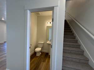 Staircase with hardwood / wood-style flooring and half bathroom