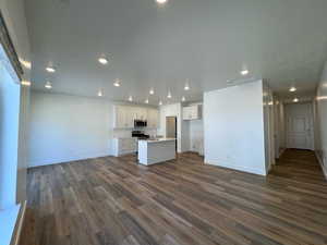 Kitchen with appliances with stainless steel finishes, sink, white cabinetry, an island with sink, and LVP flooring