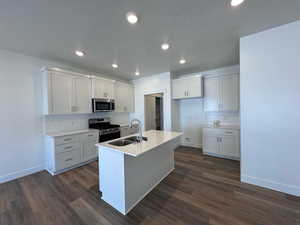 Kitchen with appliances with stainless steel finishes, LVP flooring, and white cabinetry