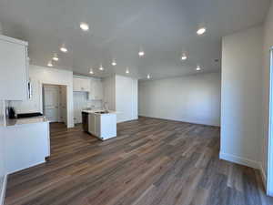 Kitchen featuring a center island with sink, white cabinets, LVP floors, stove, and sink