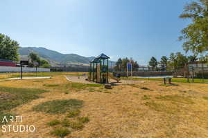 View of jungle gym with a mountain view, a fenced in pool, and a lawn