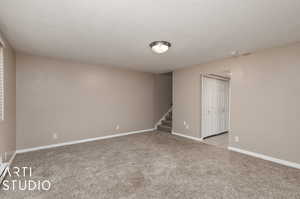 Unfurnished bedroom with light colored carpet, a closet, and a textured ceiling