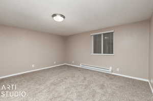 Unfurnished room featuring carpet and a baseboard heating unit