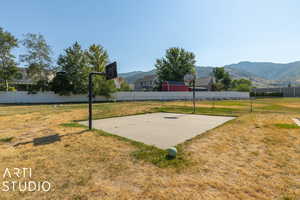 View of community featuring a mountain view, basketball hoop, and a lawn