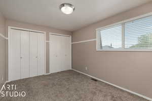 Unfurnished bedroom featuring multiple closets and carpet