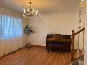 Miscellaneous room featuring an inviting chandelier, hardwood / wood-style floors, and a textured ceiling