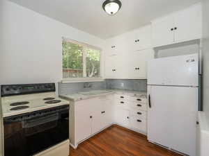 Kitchen featuring decorative backsplash, dark hardwood / wood-style floors, sink, white cabinetry, and white appliances