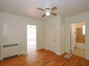 Interior space featuring radiator, ceiling fan, a healthy amount of sunlight, and light hardwood / wood-style flooring