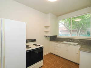 Kitchen featuring white cabinets, white electric range oven, and sink