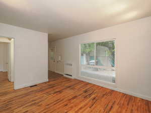 Empty room featuring hardwood / wood-style flooring and radiator heating unit