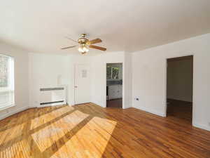 Empty room with ceiling fan, wood-type flooring, and radiator