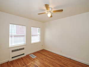 Unfurnished room with ceiling fan, hardwood / wood-style flooring, and radiator heating unit